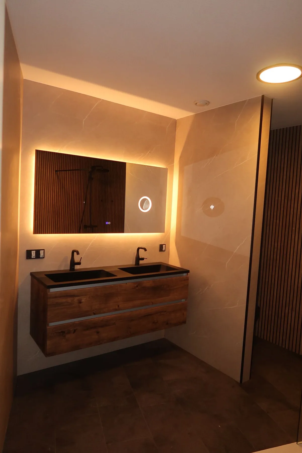 Houten dubbel wastafelmeubel met warm verlichte spiegel en marmerlook wand