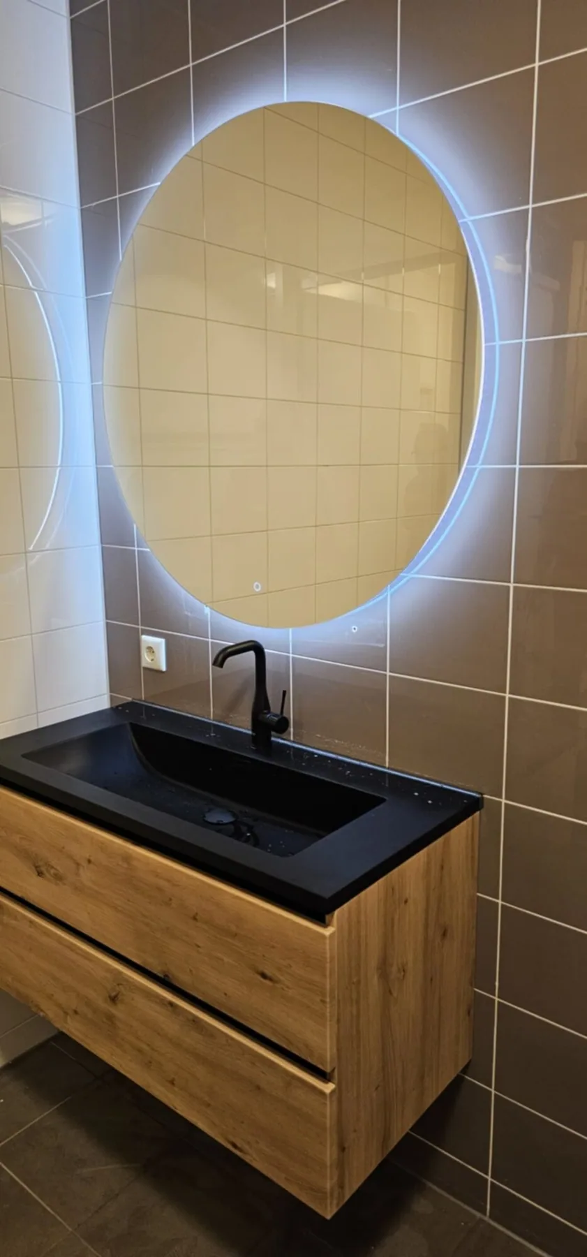 Eiken wastafelmeubel met zwarte wastafel, zwarte kraan en ronde ledspiegel
