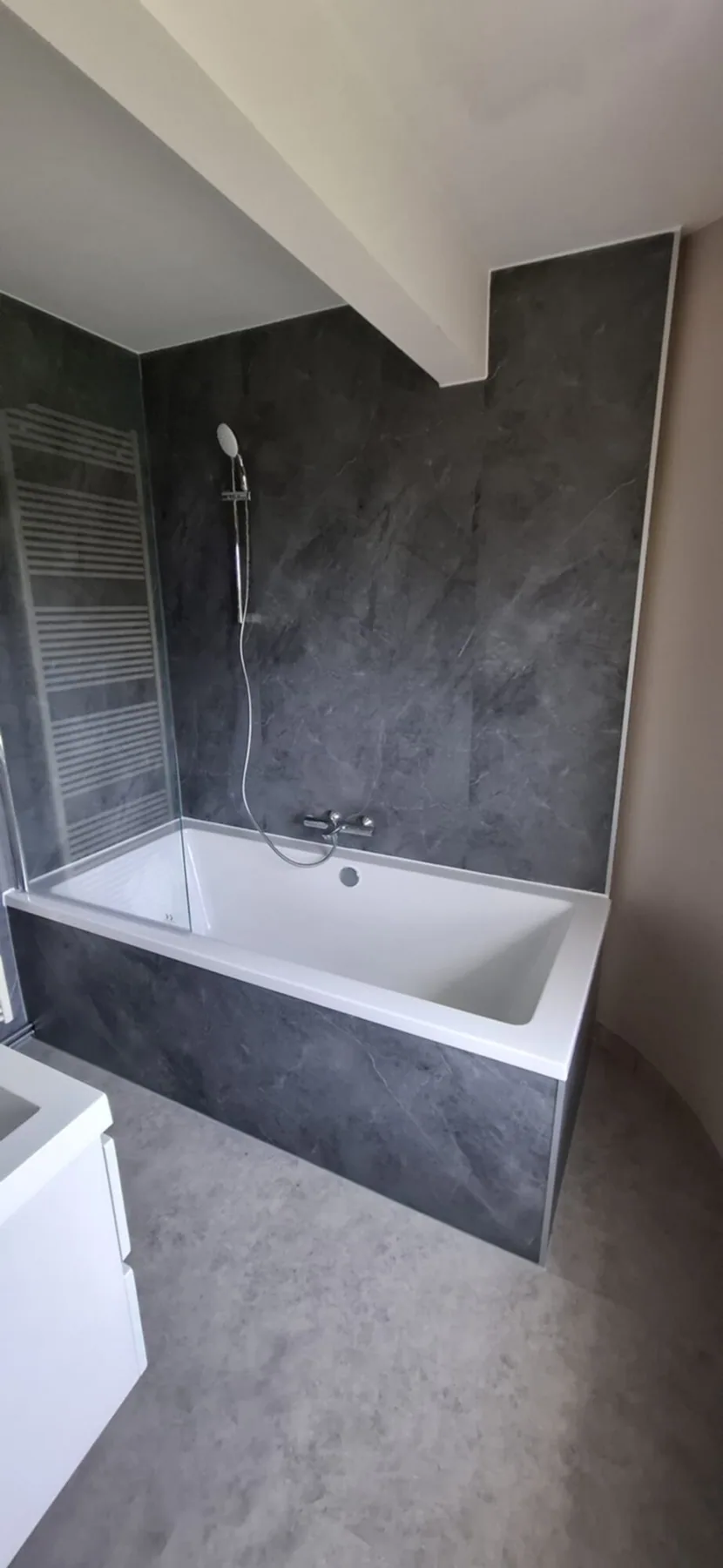 Ligbad met donkergrijze marmerlook wandpanelen en ombouw