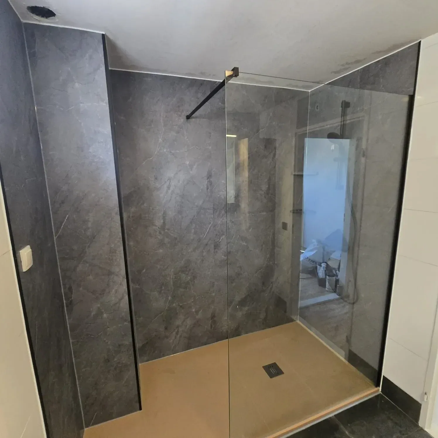 Ruime inloopdouche met glazen wanden en donkergrijze marmerlook wandpanelen