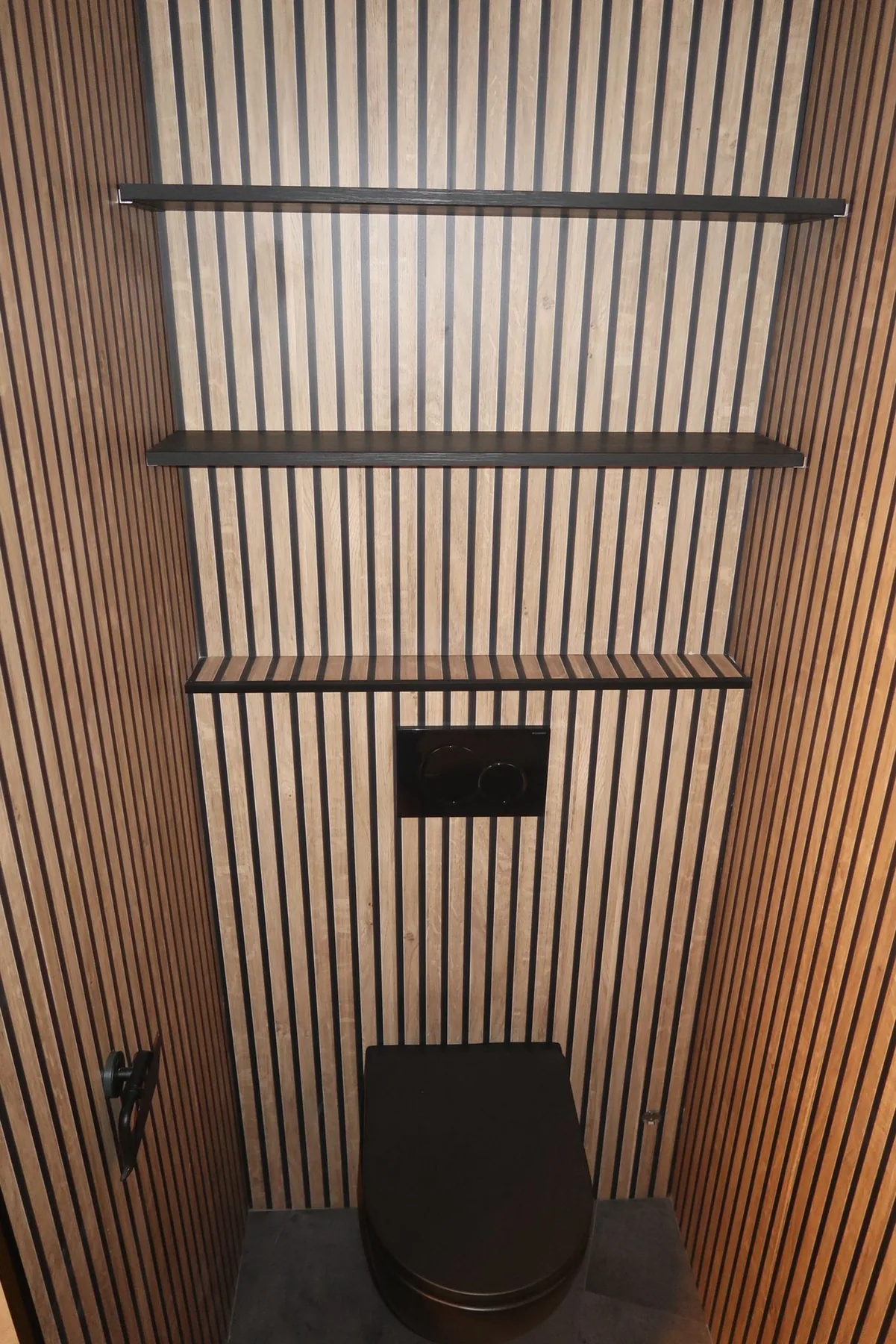 Toilet met houten lamellenwanden, zwart hangtoilet en zwarte wandplanken