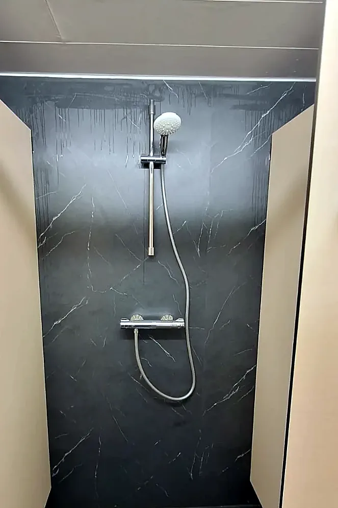Na: dezelfde douche met zwarte marmerlook wandpanelen en een nieuwe douchekraan