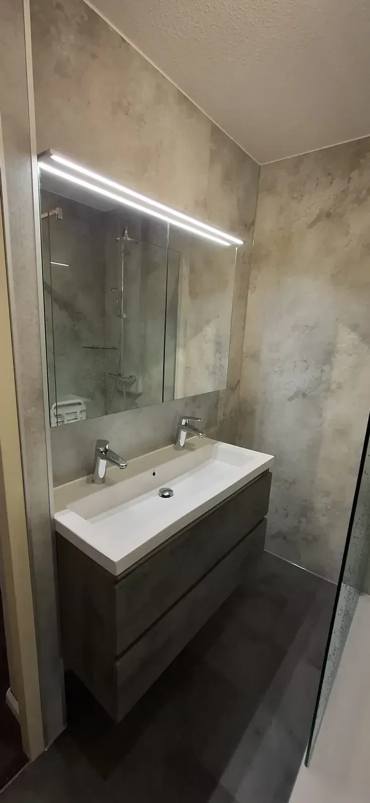 Wastafelmeubel met dubbele kraan, ledspiegelkast en beige marmerlook wandpanelen