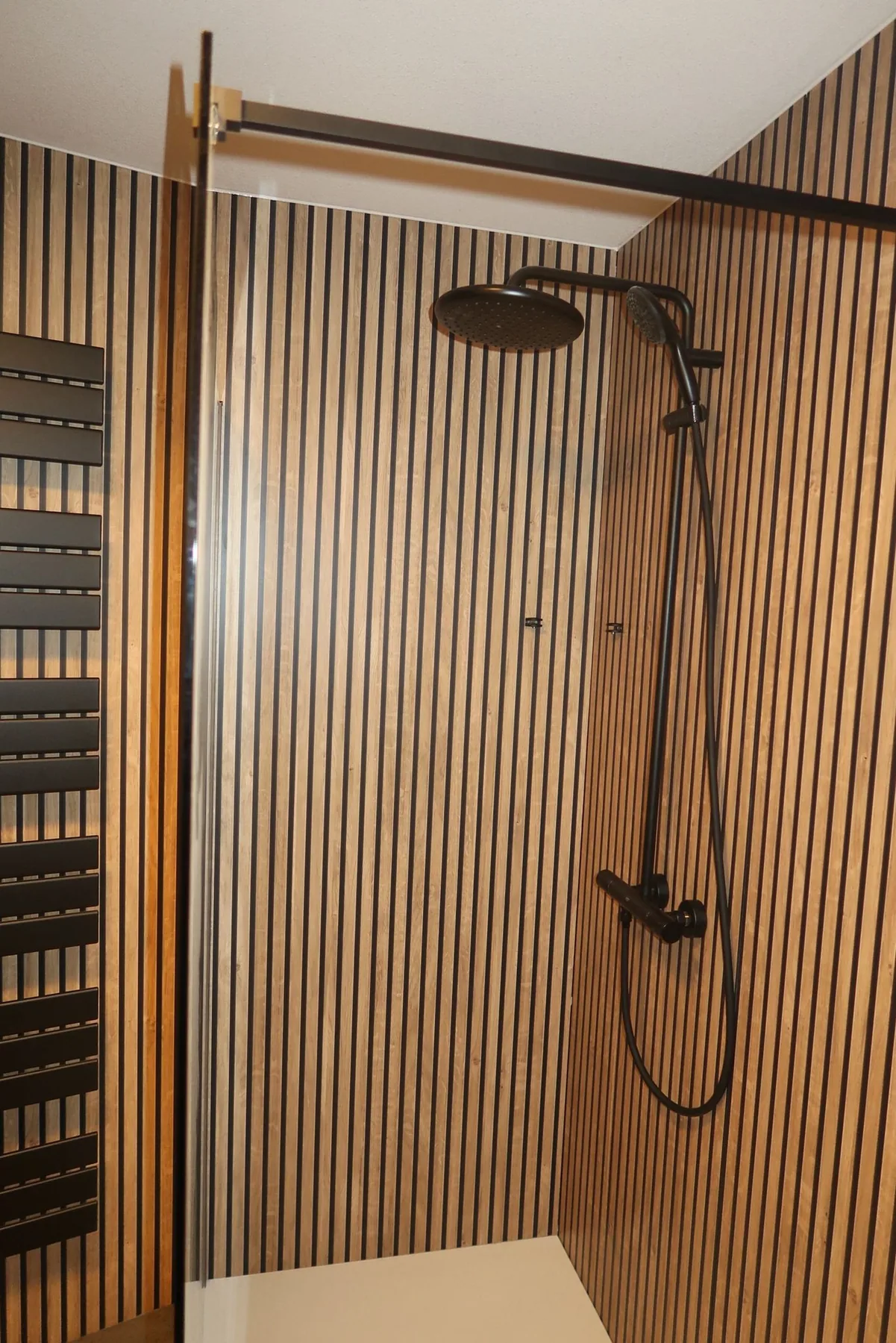 Zwarte regendouche met thermostaatkraan op houten lamellenwand